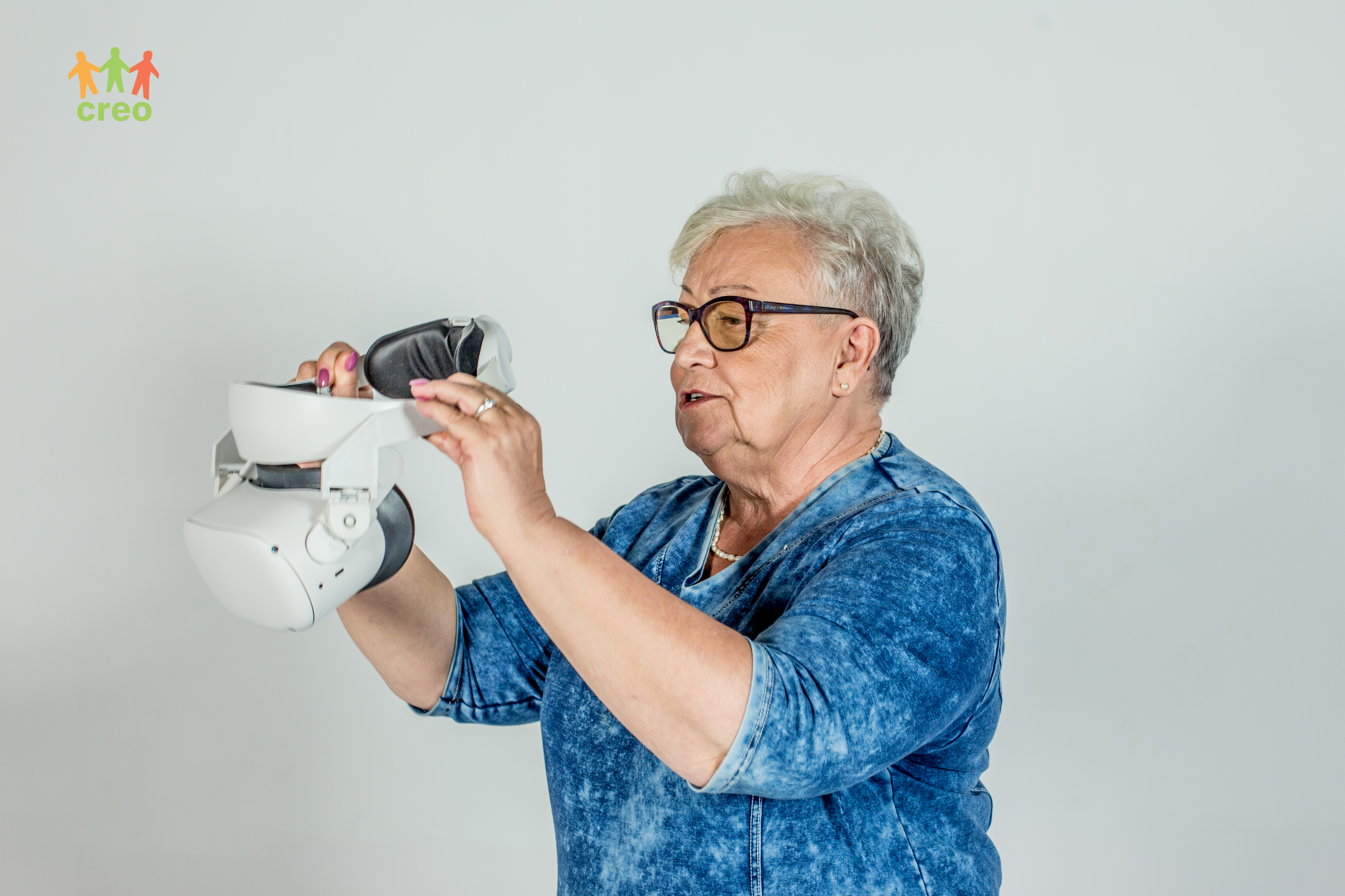 Starsza kobieta trzyma w dłoniach okulary VR.